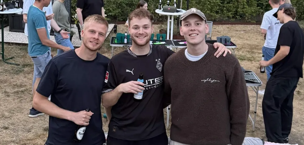 Drei Freunde auf einer Gartenparty am Beer-Pong-Tisch