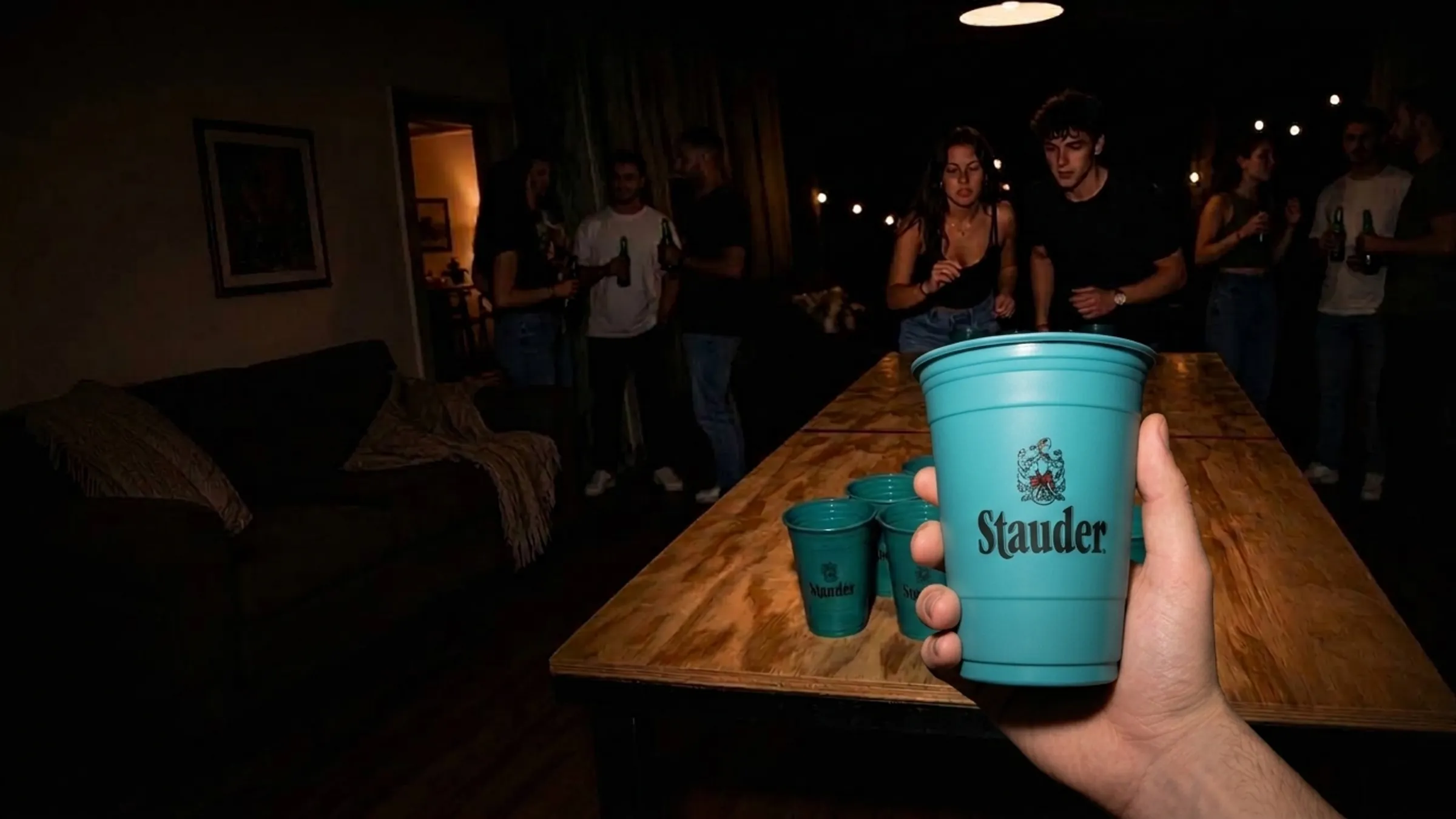 Hand mit gebrandetem Becher über einem Beer-Pong-Tisch